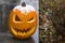 Funny carved pumpkin left over from Halloween seen on front step with snow cap