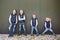 Funny Caucasian big family of three brothers and sister posing standing on growth background of wall in full growth. Equally