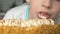 Funny Caucasian boy 6-7 years old licks cream from a cake on his birthday. Celebrating 7 years birthday. The child is eating desse