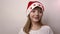 Funny caucasian girl in Santa Claus hat smiles, laughs on white background