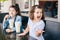 Funny Caucasian little preschool sisters siblings drink milk shakes in cafe