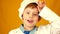 Funny Caucasian preschooler boy in the uniform of a cook close-up on a yellow background. Portrait of a tired chef child after coo