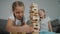 Funny caucasian sisters playing building blocks together at home, tower falls