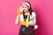 Funny charming young Caucasian housewife wearing casual t shirt and apron, orange rubber gloves, holding sponges at her face,