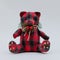 Funny checkered soft toy bear with a pine branch ornament around the neck