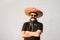 Funny and cheerful man dressed up in traditional mexican sombrero, false moustache, bandana and sunglasses. Festival or halloween