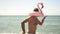 Funny cheerful man with an inflatable circle of flamingos dancing on sea beach