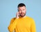 Funny cheerful  man in a yellow sweater speak by phone on blue background