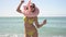 Funny cheerful woman in a swimsuit is dancing on the beach against the background of the sea in a swimming circle