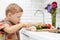 Funny child boy sets the table for dinner.little chef cuts vegetables