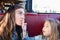 Funny child eating and giving a fried potato to her mother sitting in restaurant