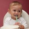 Funny child eating and holding spoon