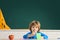 Funny child from elementary school. Children learning. Cute child boy in classroom near blackboard desk. Chalkboard copy