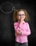 Funny child in eyeglasses standing near school chalkboard