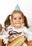 Funny child girl with birthday hat eating cake