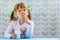 Funny child girl drinking milk with glasses straw on blue background. Growing up concept.