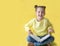 Funny child girl yellow jacket on a yellow background, sitting, reading a book, development and school concept