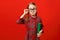 Funny child in glasses and with a book on a red background. Portrait of a serious smart little girl