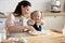 Funny child helper playing with dough helping mom in kitchen