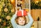 Funny child holding a red gift box with both hands. Christmas Celebration holiday. Happy little child dressed in winter