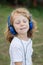 Funny child with long hair listening music with blue hadphones