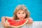 Funny child plays in the pool. The child eats a sweet watermelon, enjoy the summer. Carefree childhood.