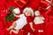 A funny child in a Santa costume lies on a red background among gifts, a Christmas tree and a snowman waiting for the new year and