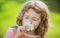 Funny child smelling plumeria flower, face close up. Kids in summer nature park, portrait.