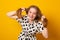 Funny child with a two-ponytail hairstyle smiles with braces grimaces and laughs on a yellow background