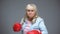 Funny childish senior lady in gloves pretending to box, self-belief concept