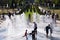 Funny children laugh and splash in fountain in the summer park. People walk in the summer park