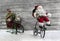 Funny christmas greeting card with Santa on a bike pulling a slide.