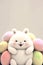 Funny Chubby Bunny Character Surrounded By Pastel Color Furry Eggs On Beige Background. Happy Easter Day Concept