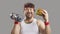 Funny chubby man holding dumbbell, eating big yummy burger and smiling at camera