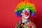 Funny clown with glasses on red