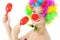 Funny clown with make up makes music with toy rattles in studio