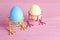 Funny colorful Easter eggs on bird legs on pink wooden backgrou