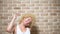 Funny comic blonde girl with fluttering curly short hair, brick wall background. copy space. Emotion concept, joy fun