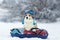 A funny corgi dog puppy in a knitted warm hat lying on a snow slide on a bun and riding in a winter park