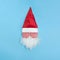 Funny crazy Head of Santa Claus in hat with lollipops eyes on blue background. Minimal Christmas concept. White beard