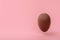 Funny creative concept of flying chocolate egg over pink background, copy space