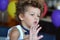 Funny curly-haired boy with butterfly on his birthday rejoices to balloons