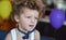 Funny curly-haired boy with butterfly on his birthday rejoices to balloons