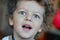 Funny curly-haired boy with butterfly on his birthday rejoices to balloons