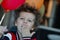 Funny curly-haired boy with butterfly on his birthday rejoices to balloons