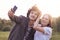 Funny curly male youngster and his girlfriend pose for making selfie portrait against blurred nature background, have positive exp