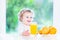 Funny curly toddler girl drinking orange juice