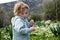 Funny cute adorable caucasian blonde baby girl, toddler in green field of daisy, camomiles smelling flowers.Curious