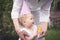 Funny cute baby girl in birthday cap playing with mother in park during birthday party