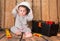 Funny cute baby in helmet playing with tools on wooden background.